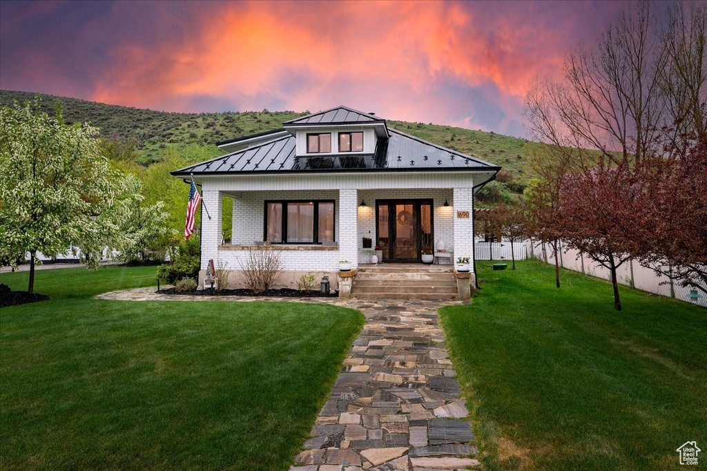 View of front of property with covered porch, a standing seam roof, brick siding, a mountain view, and metal roof