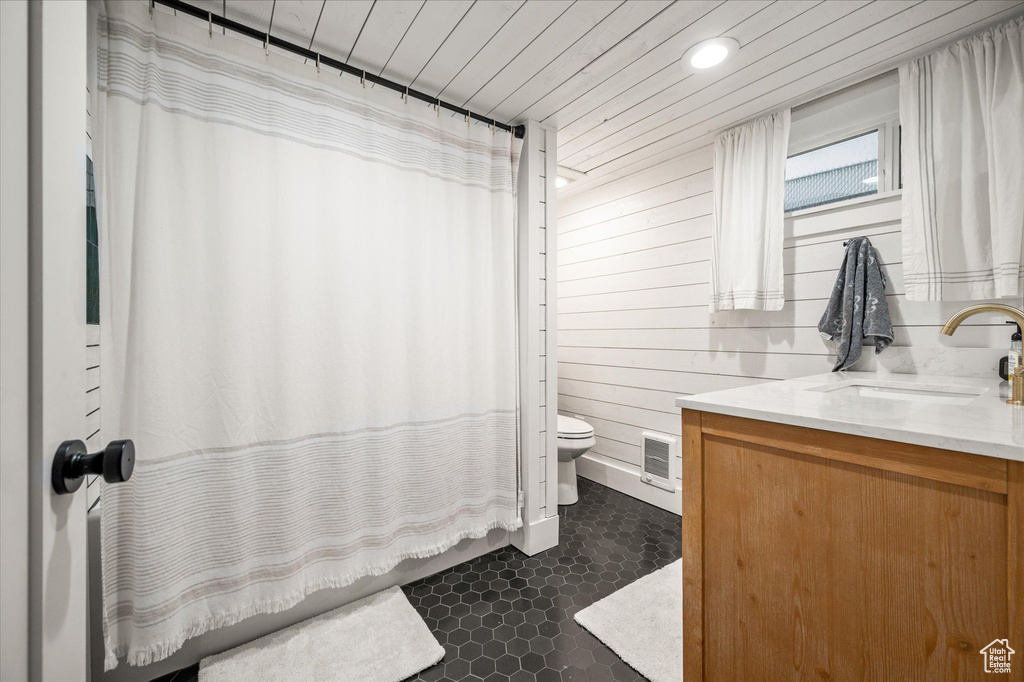 Full bathroom featuring vanity, toilet, recessed lighting, a shower with curtain, and wood walls