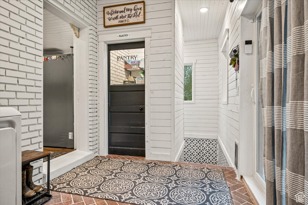 Foyer featuring wood walls and brick patterned floors