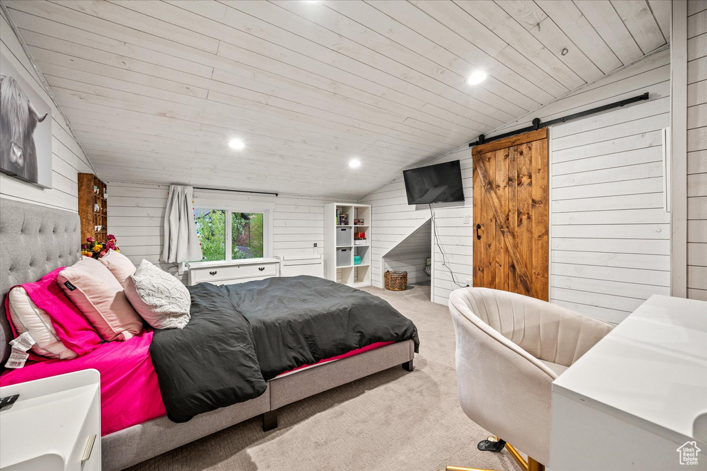 Carpeted bedroom featuring vaulted ceiling, a barn door, wood ceiling, wood walls, and recessed lighting