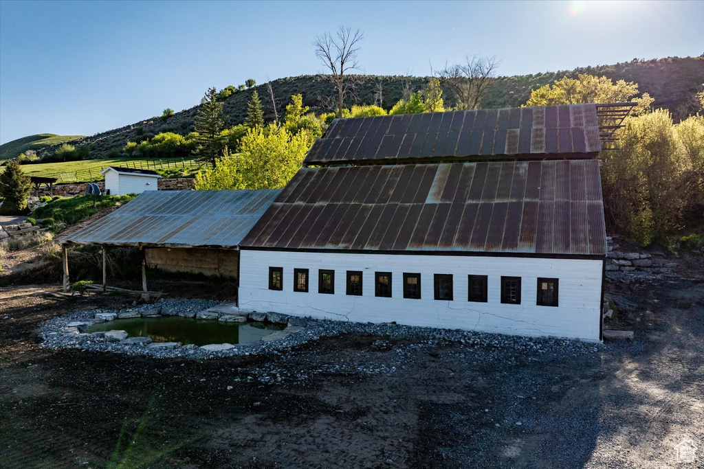 View of side of property featuring an outdoor structure, a mountain view, and metal roof