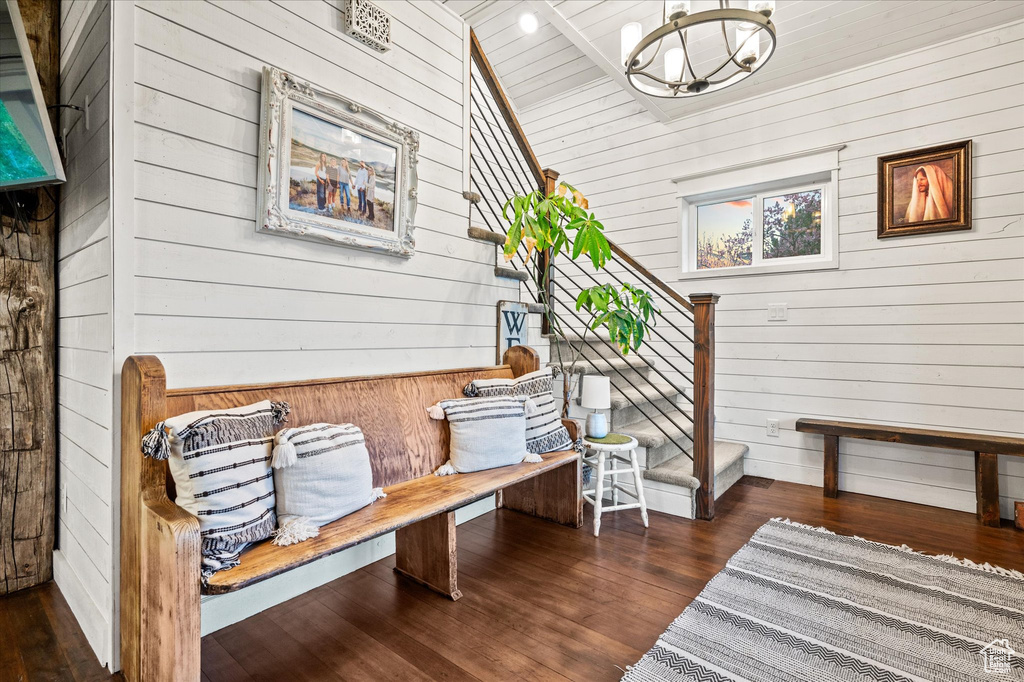 Sitting room with wood walls, a chandelier, and wood finished floors