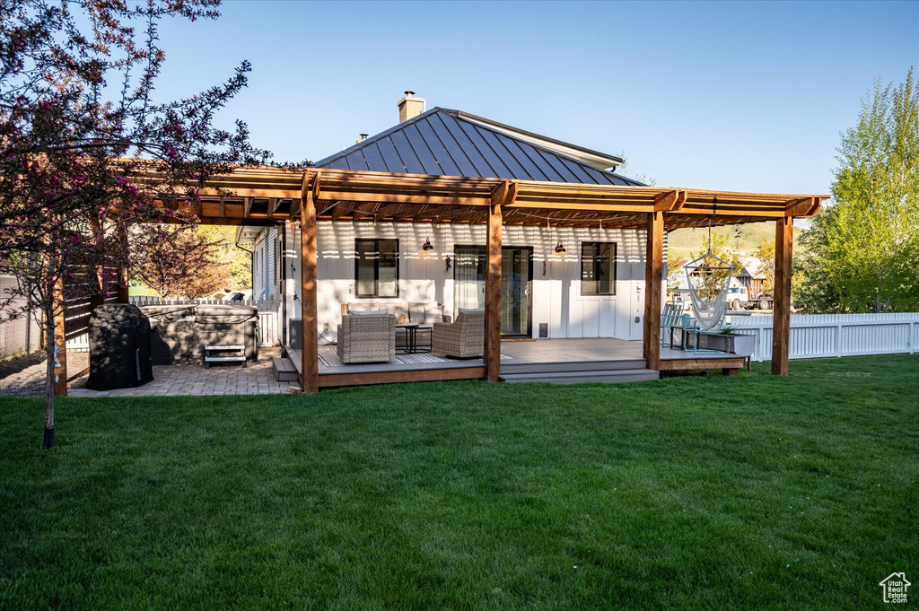 Back of house with a standing seam roof, a wooden deck, a chimney, metal roof, and board and batten siding
