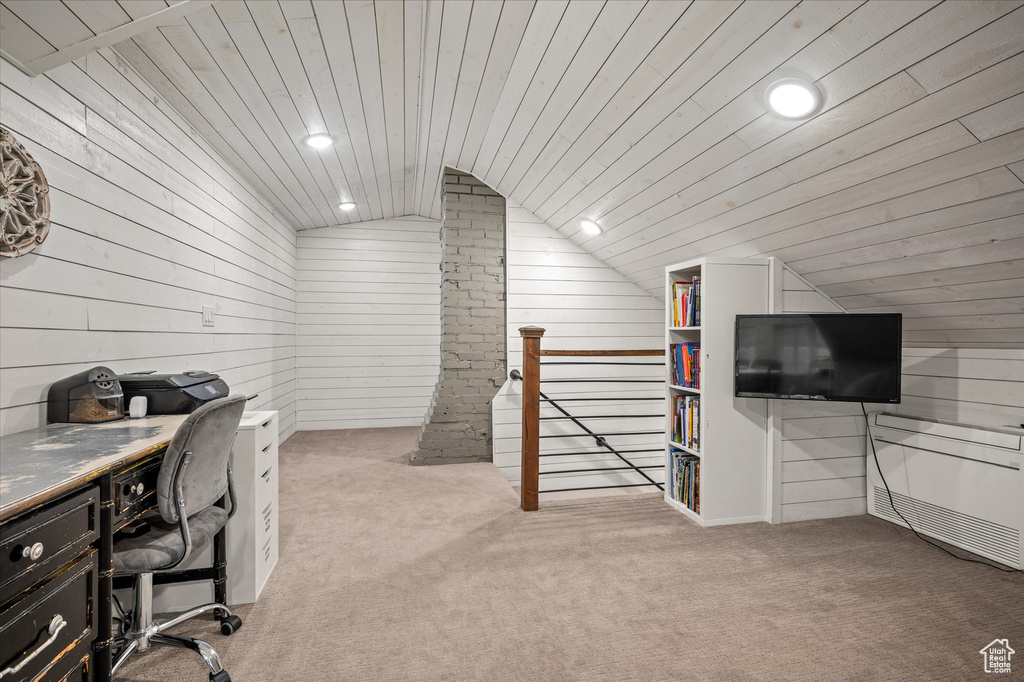 Office space with lofted ceiling, light colored carpet, wooden walls, and recessed lighting