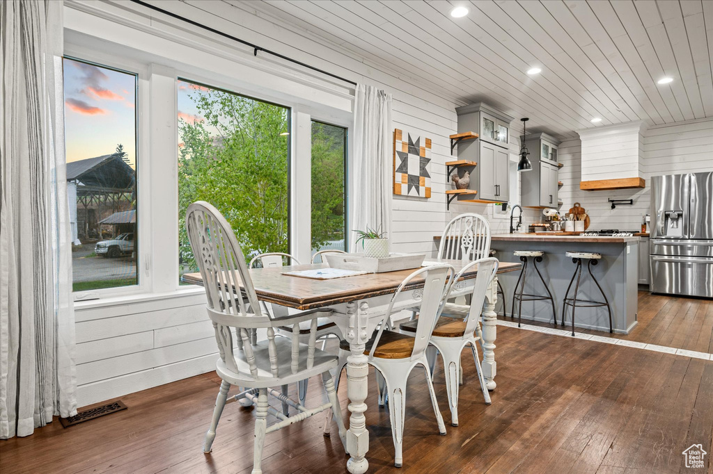 Dining room featuring recessed lighting, dark wood-style flooring, and wooden walls