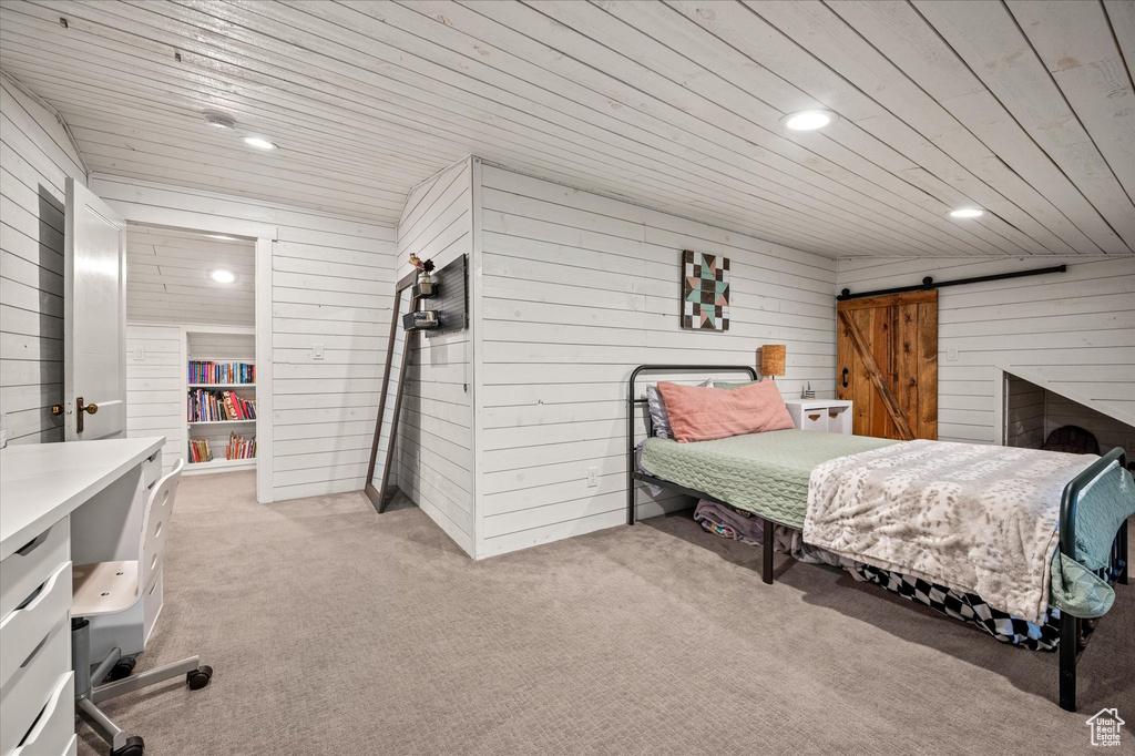 Bedroom featuring wood ceiling, wooden walls, light colored carpet, a barn door, and recessed lighting