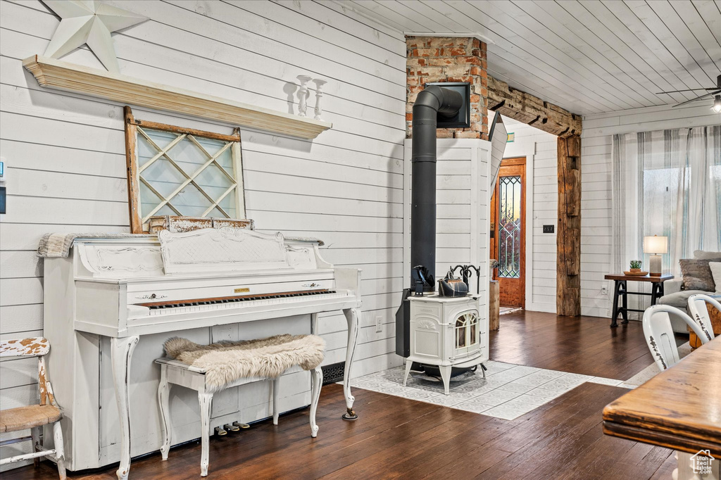 Misc room with a wood stove, wood walls, dark wood-type flooring, and wood ceiling