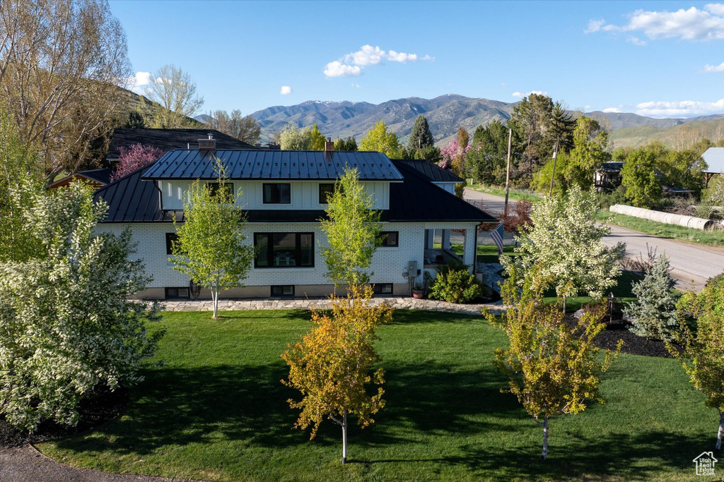 Rear view of property featuring a standing seam roof, a mountain view, and a yard