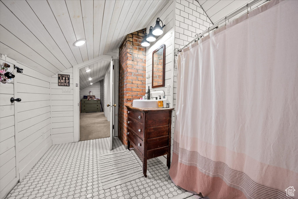 Full bath featuring vaulted ceiling, vanity, curtained shower, wood ceiling, and wood walls