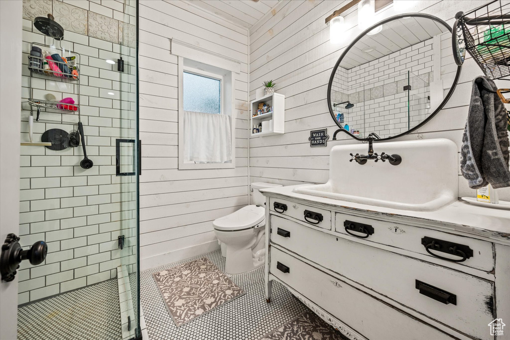 Full bath featuring a shower stall, vanity, tile patterned floors, toilet, and wooden walls