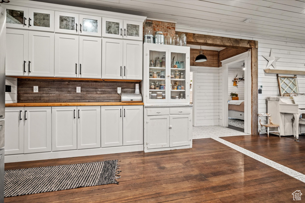 Kitchen featuring wooden counters, white cabinets, wooden walls, hanging light fixtures, and glass insert cabinets