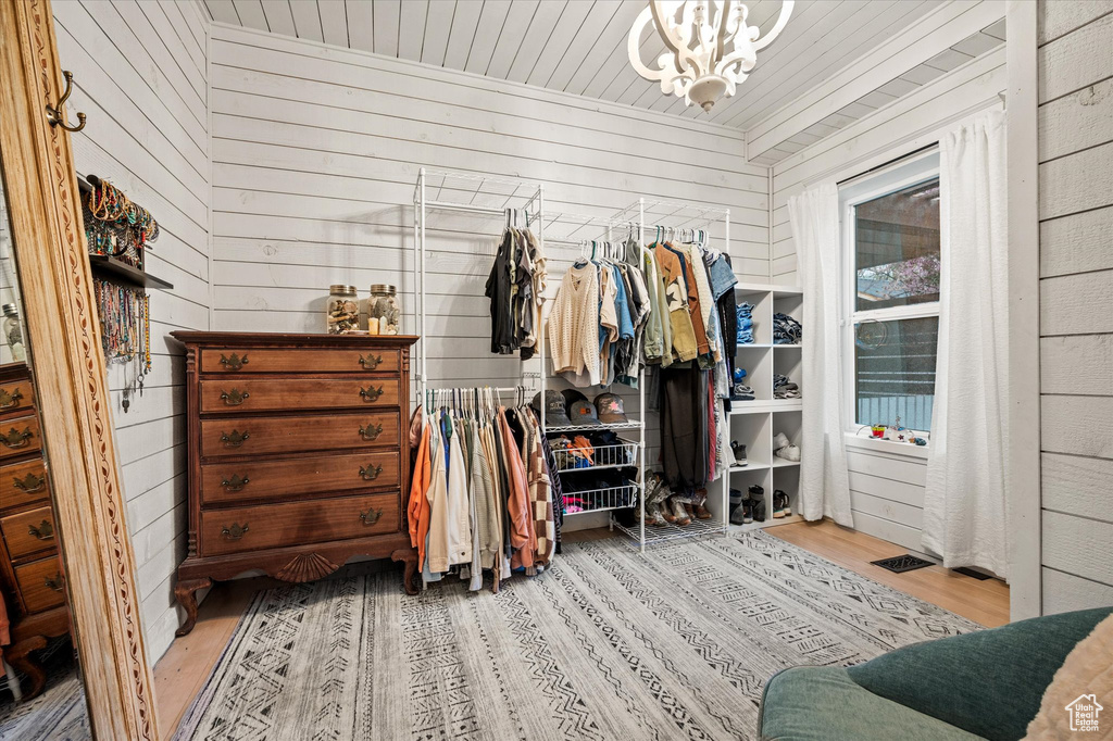 Walk in closet with wood finished floors and a chandelier
