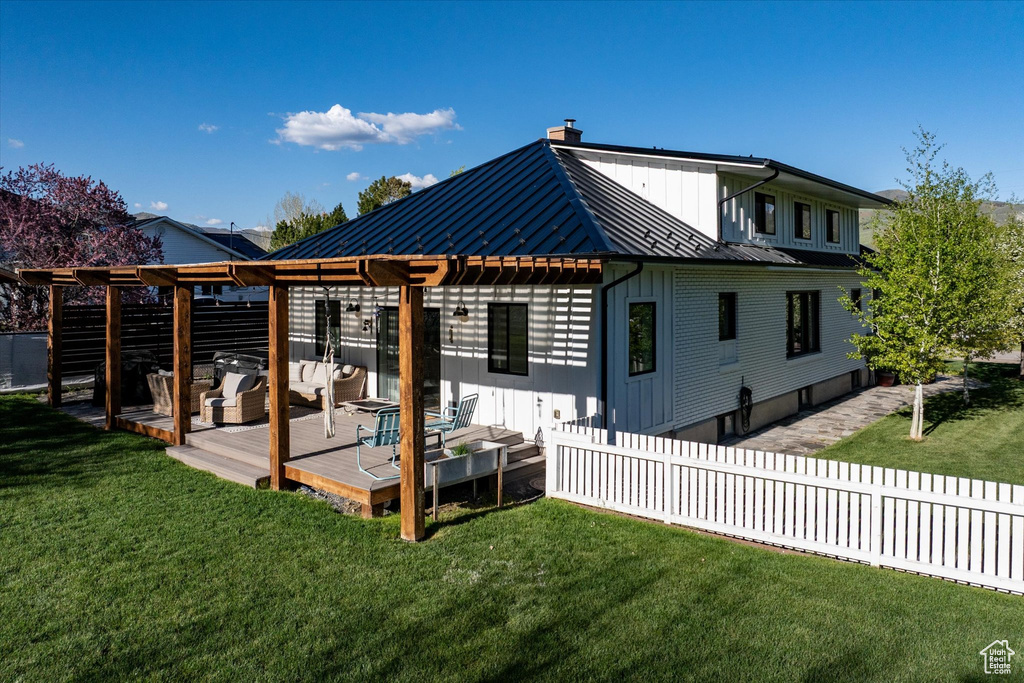Back of property featuring a pergola, metal roof, a chimney, a deck, and a standing seam roof