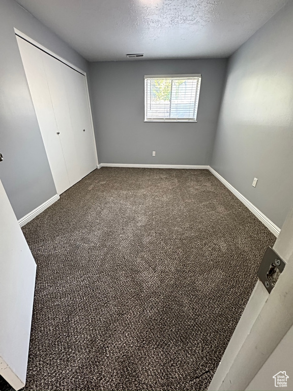 Unfurnished bedroom featuring a closet, carpet floors, baseboards, and a textured ceiling