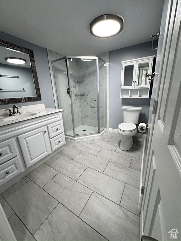 Full bath with marble look tiles, vanity, a stall shower, and toilet