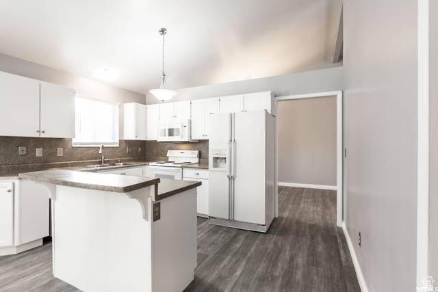 Kitchen with white appliances, a sink, tasteful backsplash, and dark wood finished floors