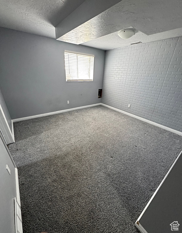Unfurnished room featuring a textured ceiling, carpet floors, and baseboards