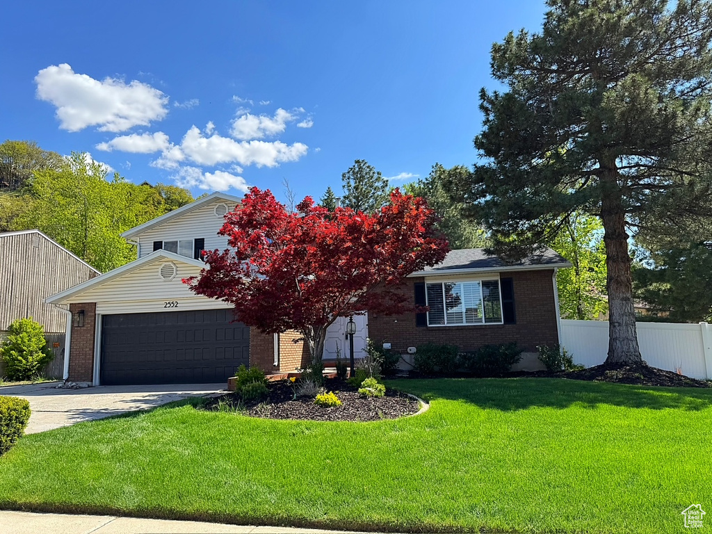 View of front of home with brick siding, a garage, and driveway