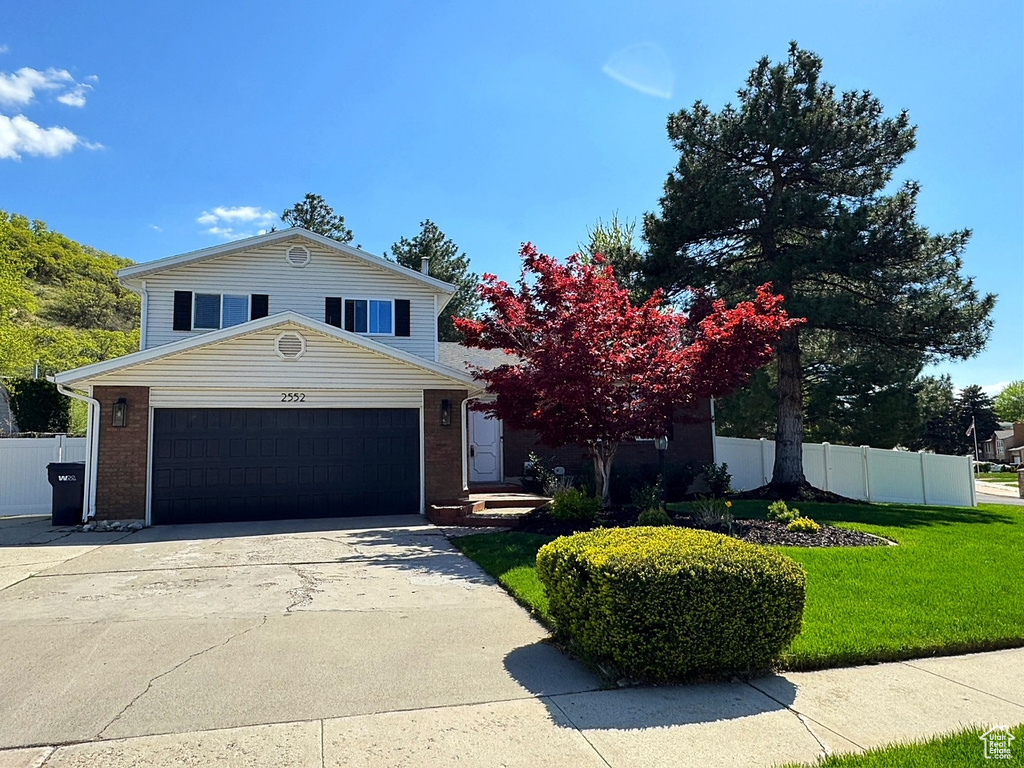 View of front of home with a garage, driveway, and brick siding