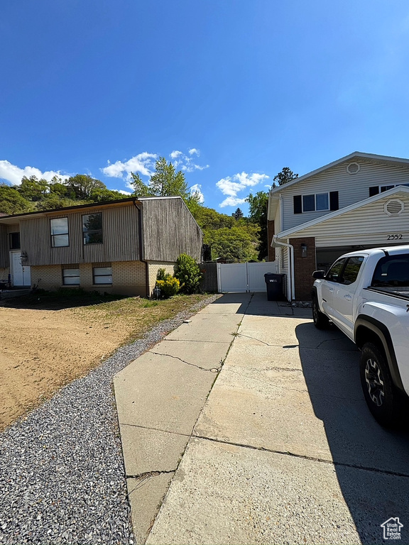 View of side of property featuring driveway, a gate, and fence