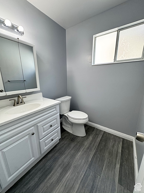 Bathroom featuring toilet, wood finished floors, vanity, and baseboards