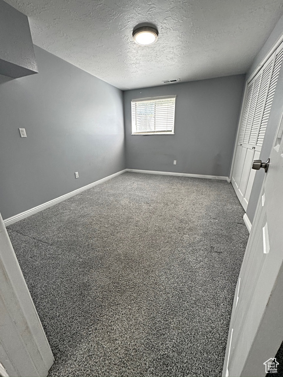 Unfurnished bedroom featuring a textured ceiling, baseboards, and carpet floors