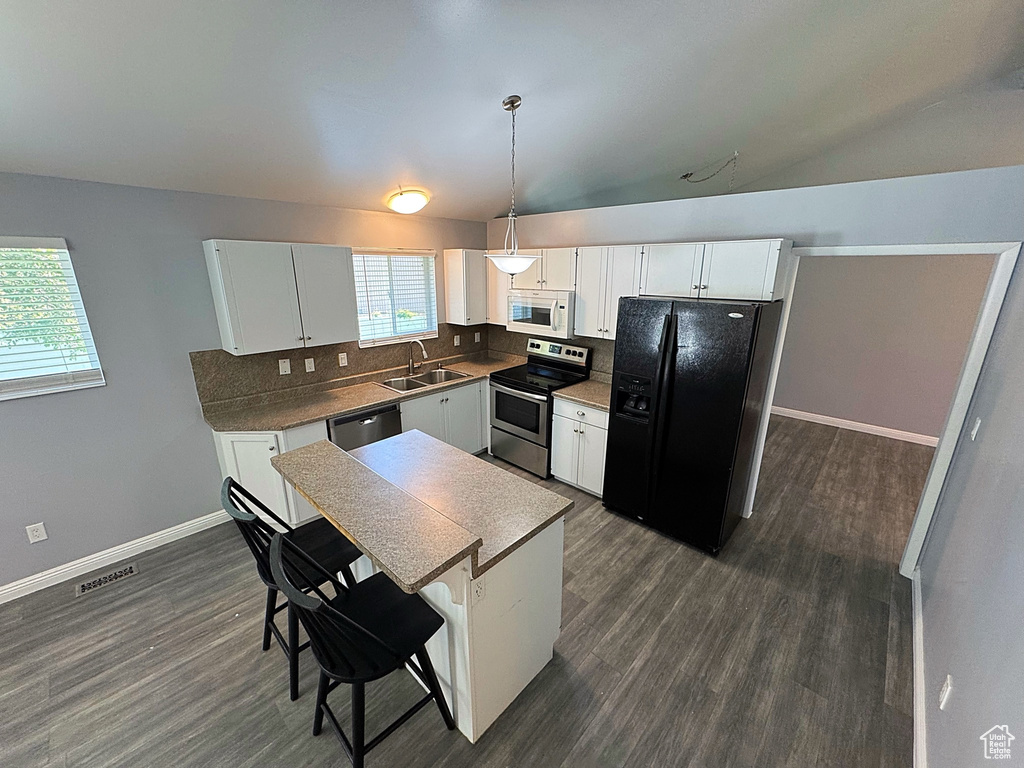 Kitchen with stainless steel appliances, a sink, decorative backsplash, dark wood-style flooring, and vaulted ceiling