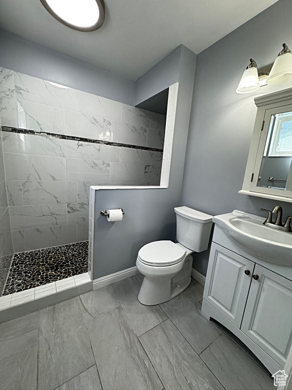 Bathroom featuring marble finish flooring, baseboards, a walk in shower, toilet, and vanity
