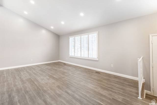 Unfurnished room featuring wood finished floors, baseboards, and recessed lighting