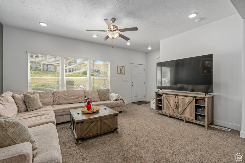 Living area with a ceiling fan, light colored carpet, recessed lighting, baseboards, and a textured ceiling
