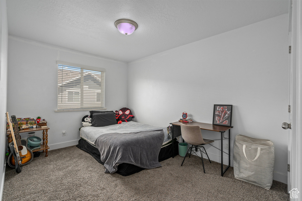 Carpeted bedroom with baseboards and a textured ceiling