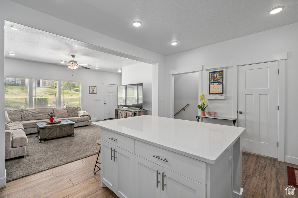 Kitchen with open floor plan, light wood-style floors, light countertops, a kitchen island, and recessed lighting