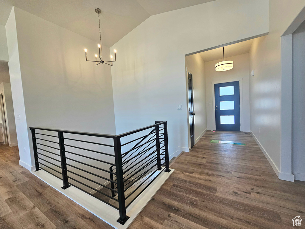 Foyer entrance featuring a chandelier, wood finished floors, baseboards, and high vaulted ceiling