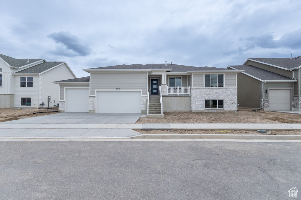 Single story home featuring an attached garage, concrete driveway, and stone siding