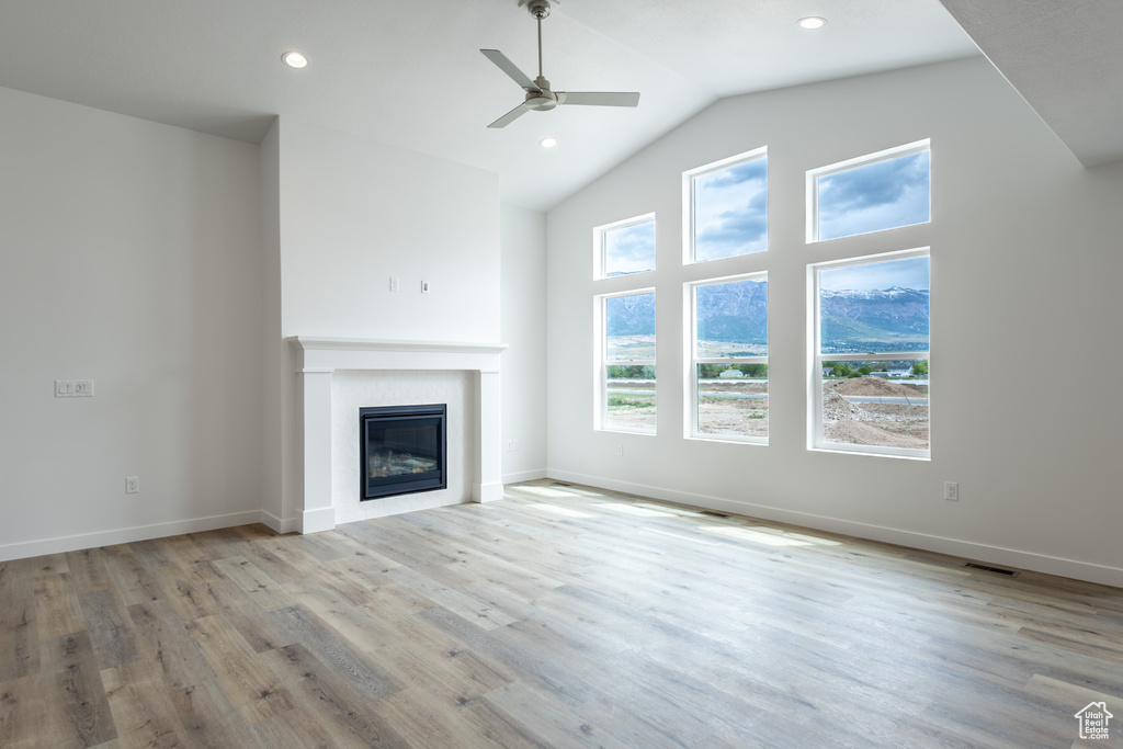Unfurnished living room with ceiling fan, a glass covered fireplace, wood finished floors, recessed lighting, and baseboards