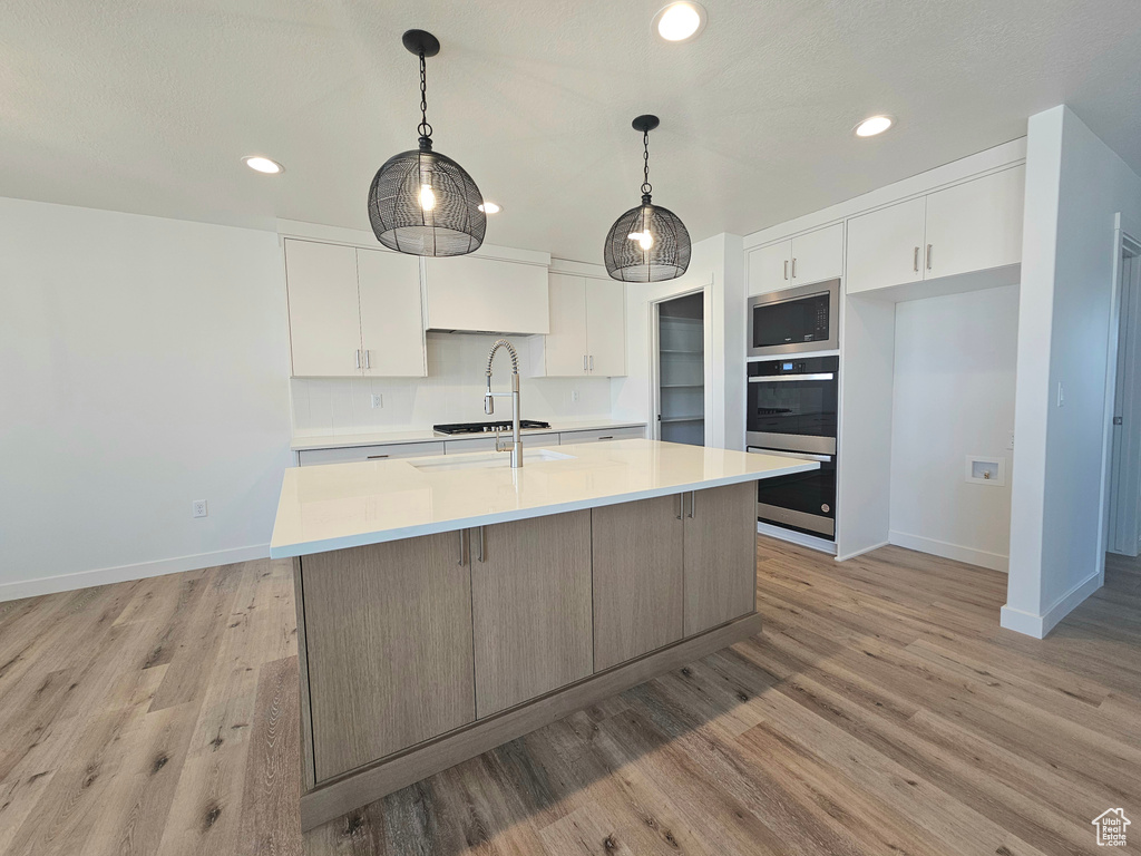 Kitchen with baseboards, recessed lighting, white cabinets, and light countertops