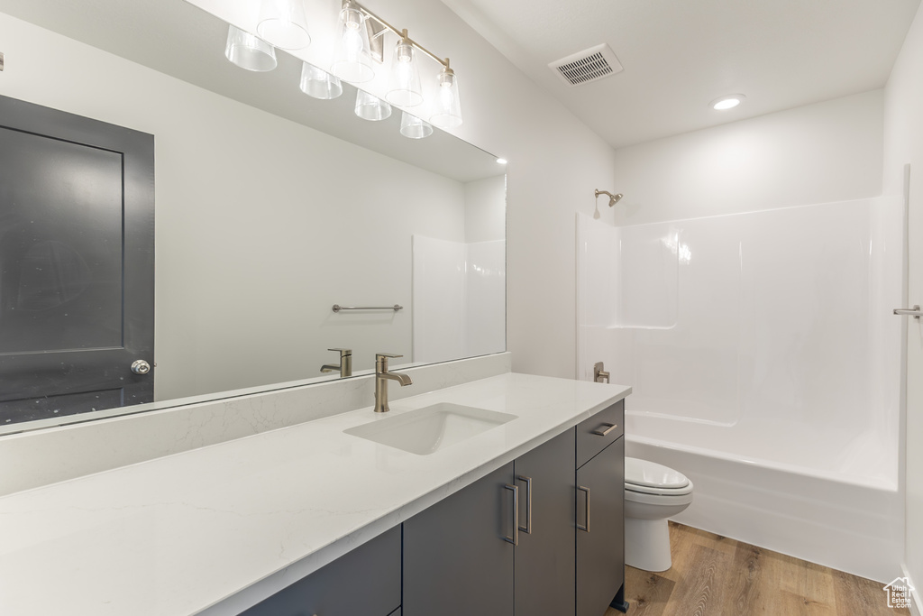 Full bathroom with toilet, vanity, shower / tub combination, and wood finished floors