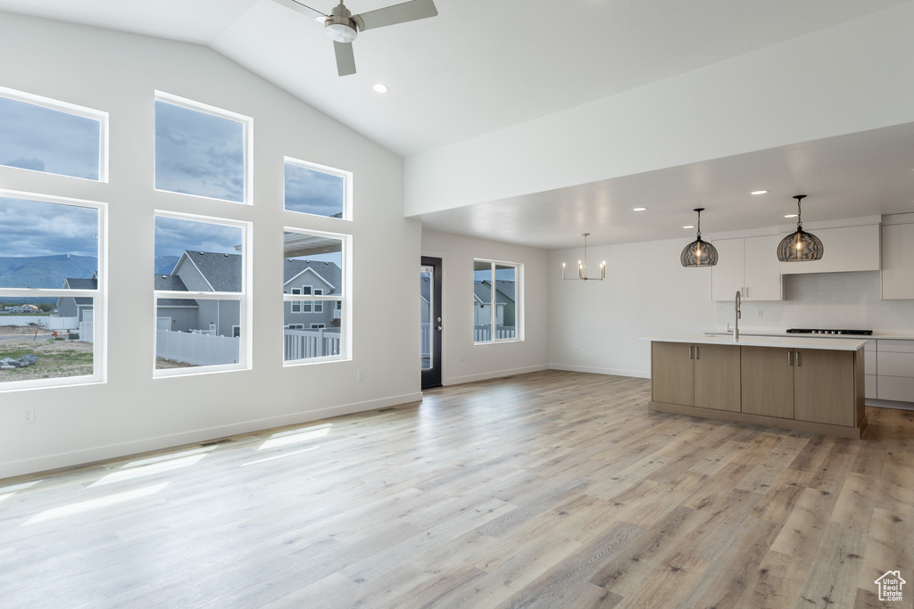 Unfurnished living room with a sink, a chandelier, a ceiling fan, light wood-type flooring, and recessed lighting