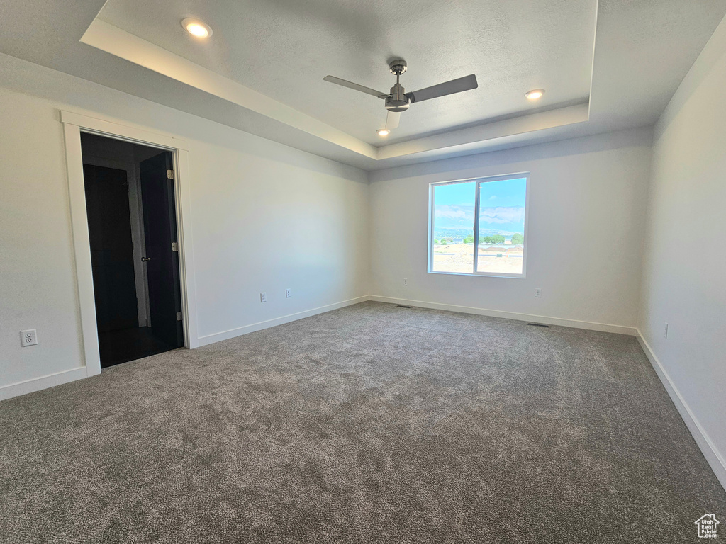 Unfurnished room featuring a tray ceiling, carpet floors, a ceiling fan, baseboards, and recessed lighting