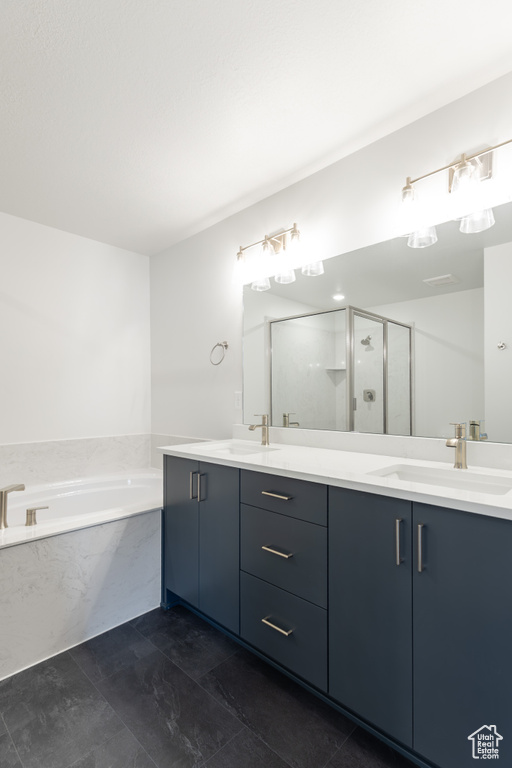 Bathroom featuring a bath, a stall shower, and double vanity