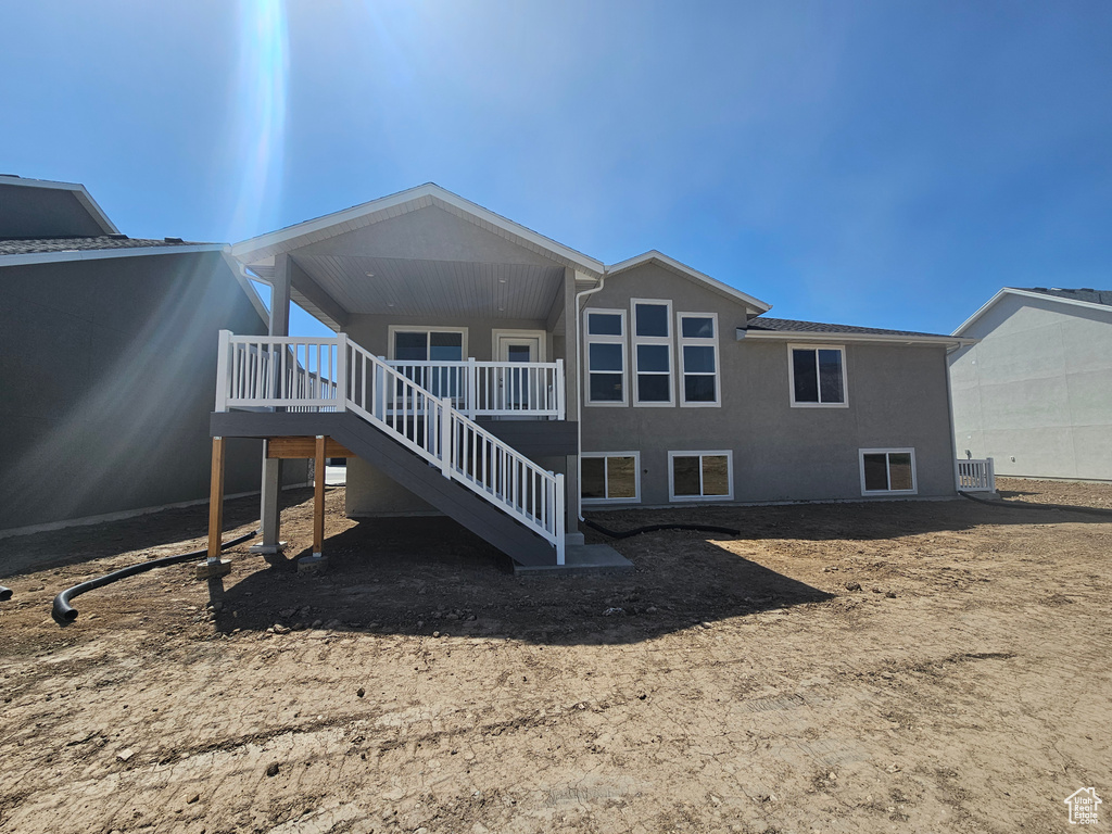 Rear view of property with stairway, cooling unit, stucco siding, and a wooden deck