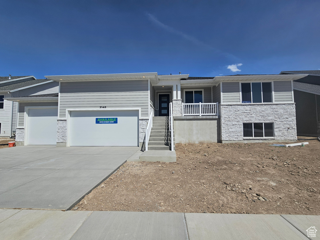 View of front of home featuring stone siding, an attached garage, driveway, and stairs