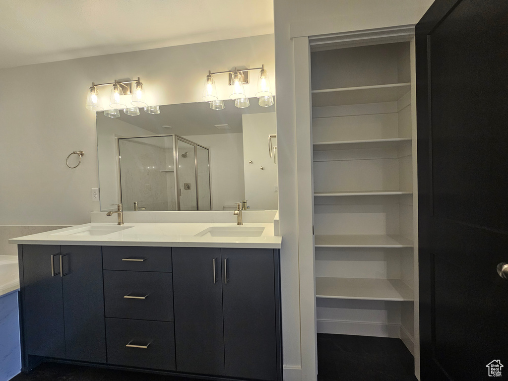 Full bath featuring a shower stall, a spacious closet, and double vanity