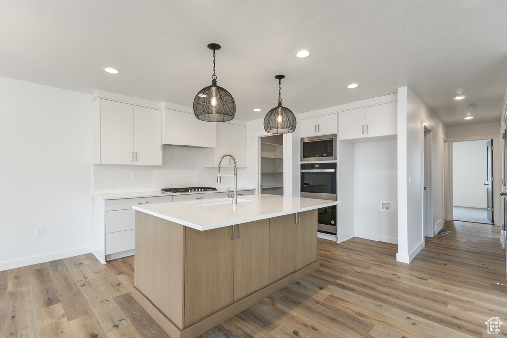Kitchen with stainless steel appliances, a sink, baseboards, recessed lighting, and light countertops