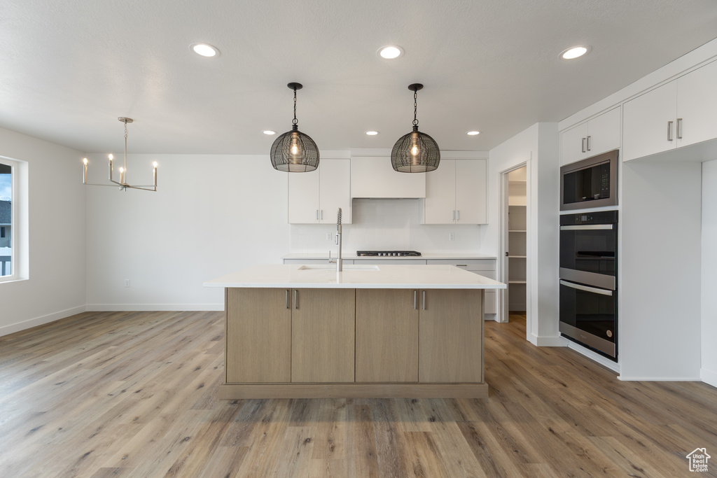 Kitchen with built in microwave, double oven, light countertops, recessed lighting, and light wood finished floors