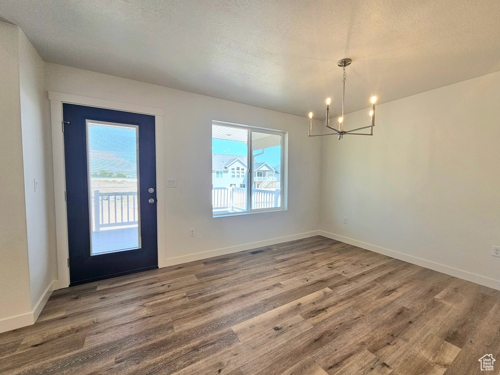 Entrance foyer featuring a chandelier, plenty of natural light, wood finished floors, a textured ceiling, and baseboards