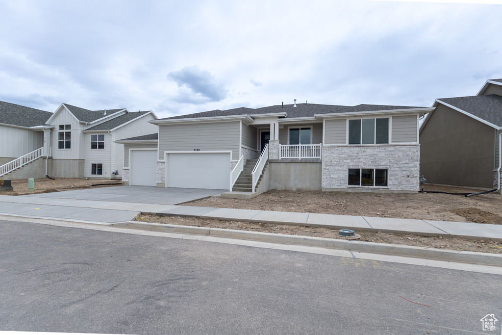 View of front of home with driveway, stairway, a garage, and stone siding