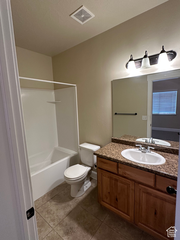 Full bathroom featuring tile patterned floors, toilet, vanity, and  shower combination