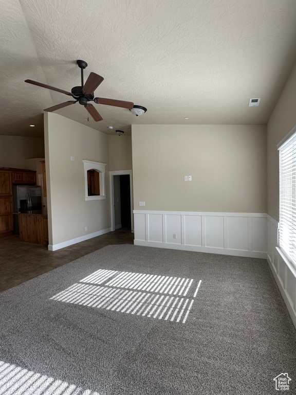 Unfurnished room with carpet, a ceiling fan, and a textured ceiling