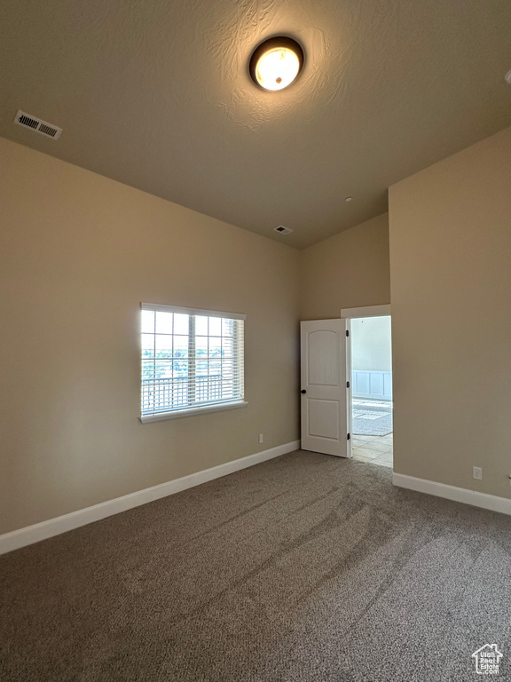 Spare room with lofted ceiling, carpet floors, and baseboards